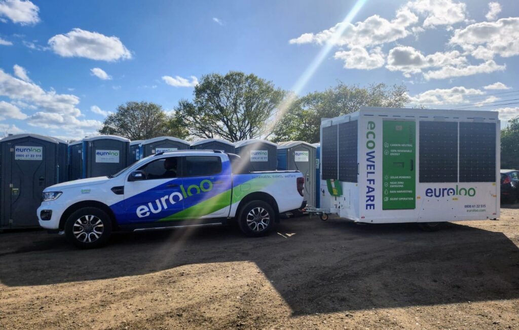Euroloo Vehicle Towing Solar-Powered Ecowelfare Unit Beside Portable Site Toilets Under A Blue Sky