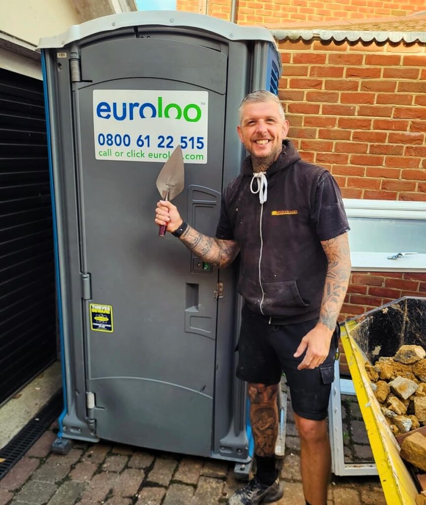 Matt Greenley Of Mg Brickwork In Essex Standing In Front Of A Euroloo Portable Toilet