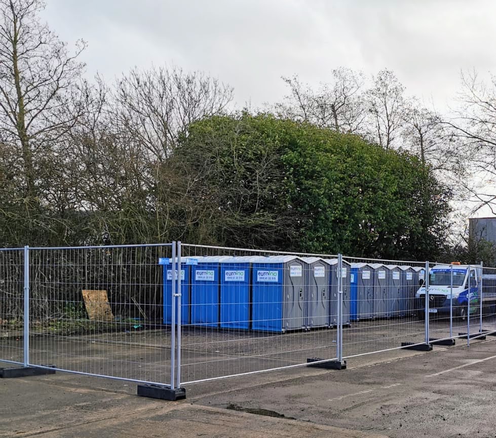 Heras Fencing Panels Set Up On A Uk Construction Site With A Euroloo Portable Toilet In The Background